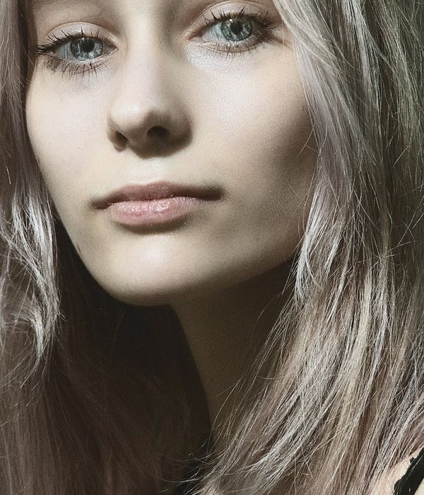 Woman with calm and focused eyes looking forward, surrounded by soft cyan light.